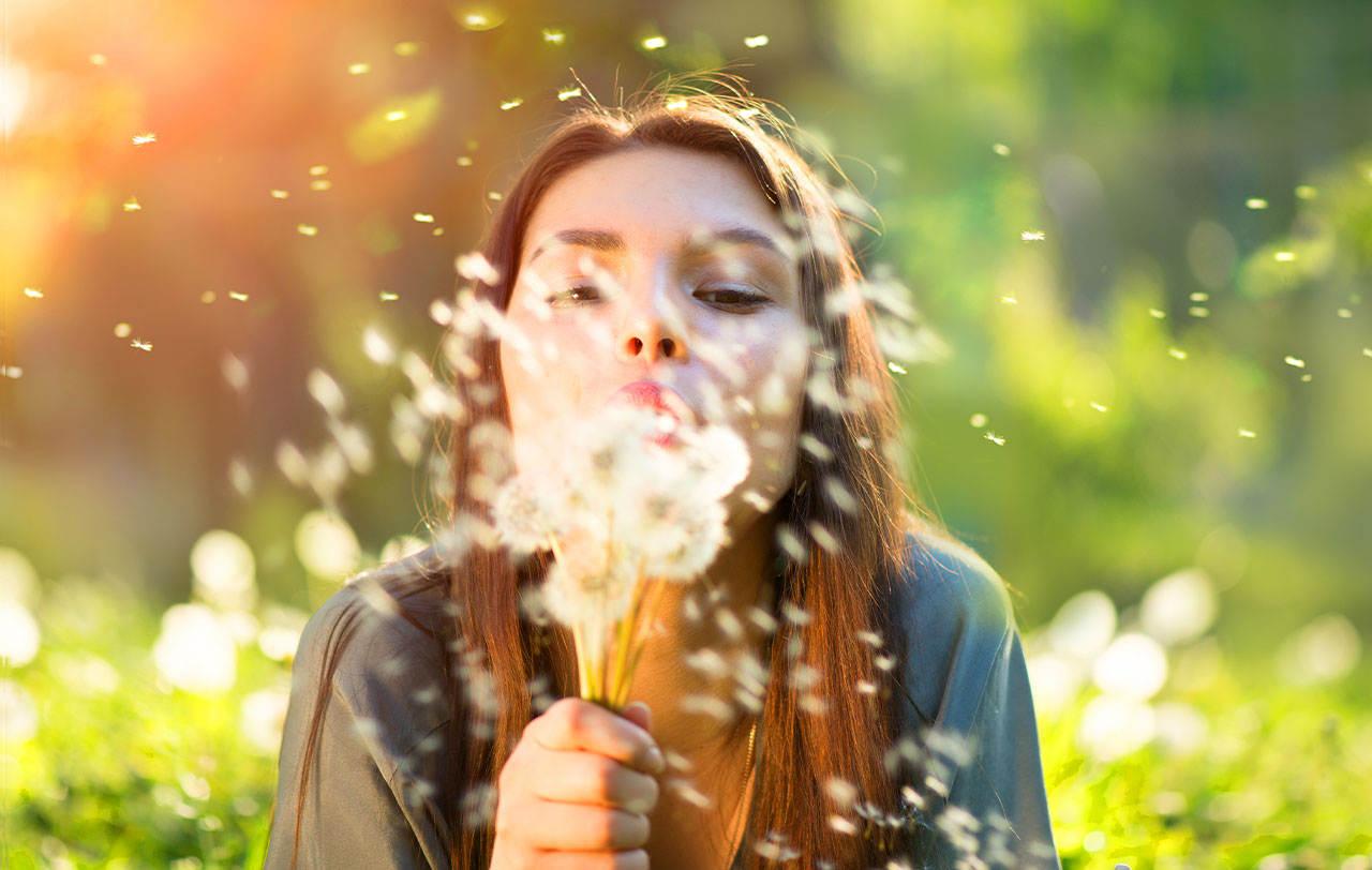 Woman blowing a dandelion into the wind