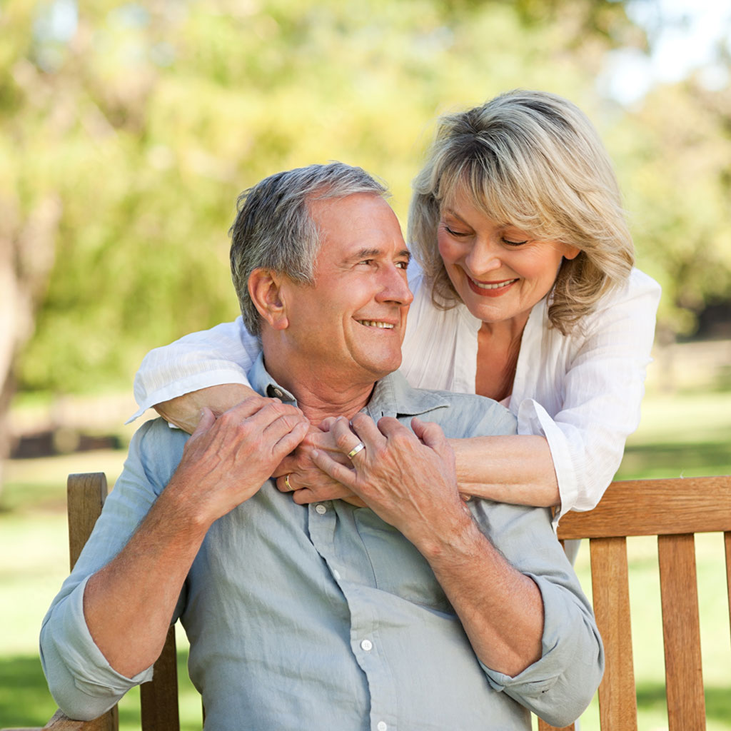 Smiling Elderly Couple Seated Outside