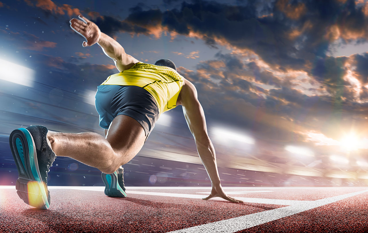 Runner in blue shorts and yellow shirt crouched for the start of a run